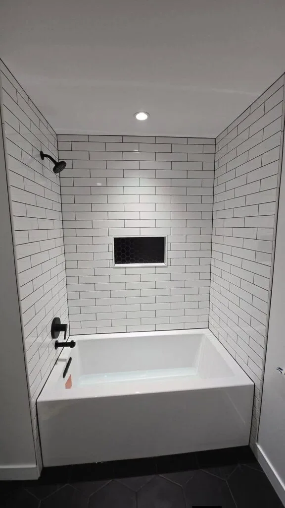 Renovated Fort Rouge bathroom with tiled tub surround and niche