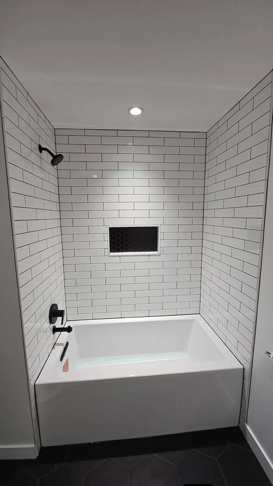 Renovated Fort Rouge bathroom with tiled tub surround and niche