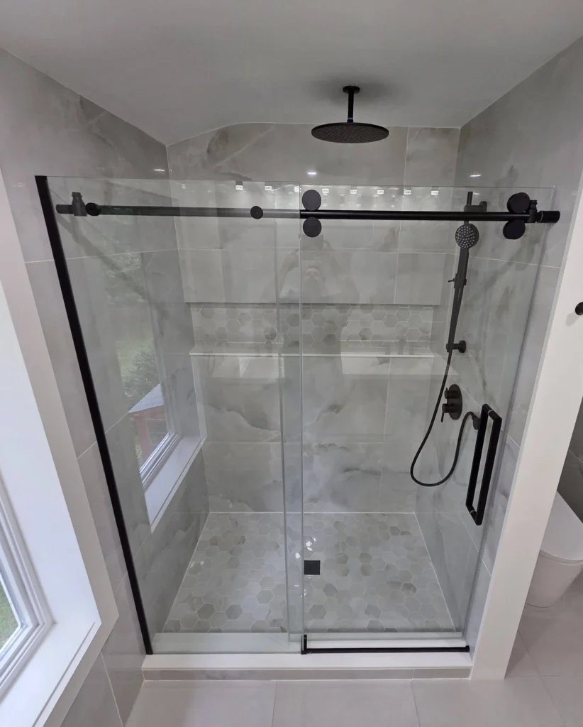 Renovated River Heights bathroom with a glass walk-in shower, rain head and handheld, and large-format marble-look porcelain tile