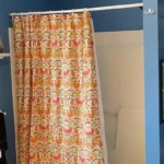 River Heights bathroom before renovation, with the original alcove bathtub behind a floral shower curtain and blue-painted walls