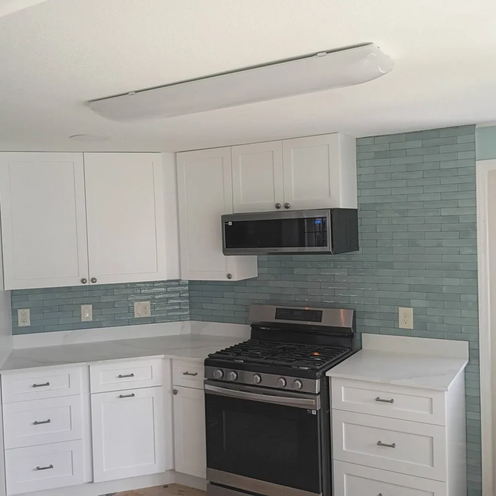 Renovated Island Lakes kitchen with white cabinets and glass tile backsplash