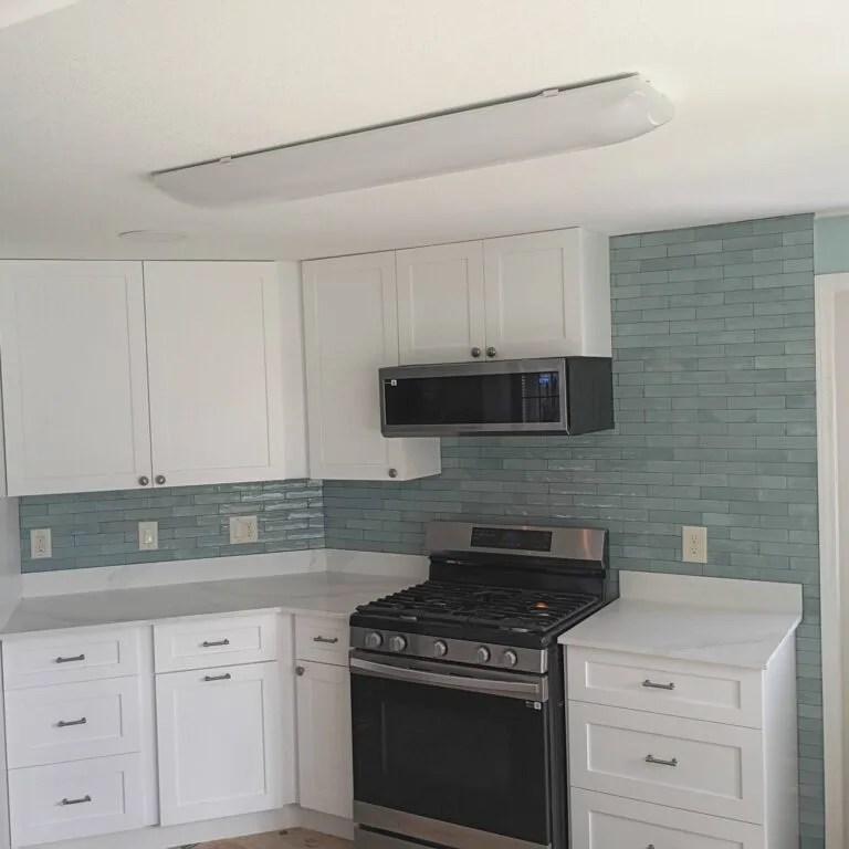 Renovated Island Lakes kitchen with white cabinets and glass tile backsplash