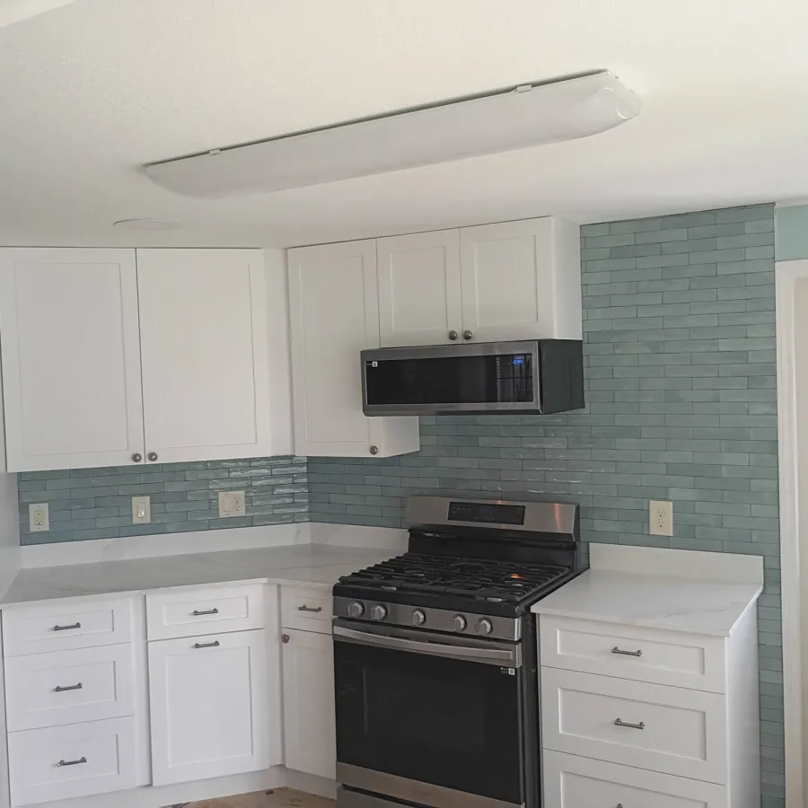 Renovated Island Lakes kitchen with white cabinets and glass tile backsplash
