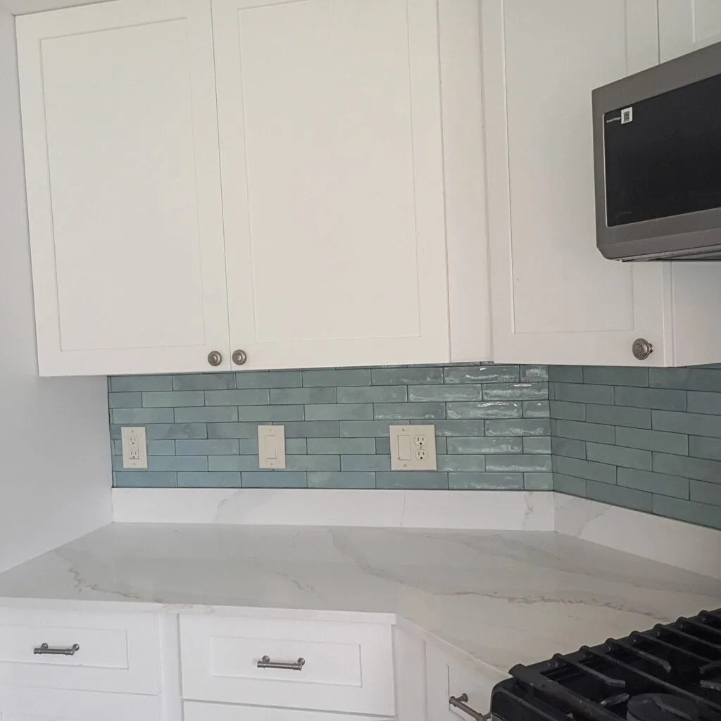 Island Lakes kitchen corner cabinetry and quartz countertop with green glass-tile backsplash