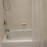 Crescentwood bathroom before renovation, with the original bathtub and shower curtain