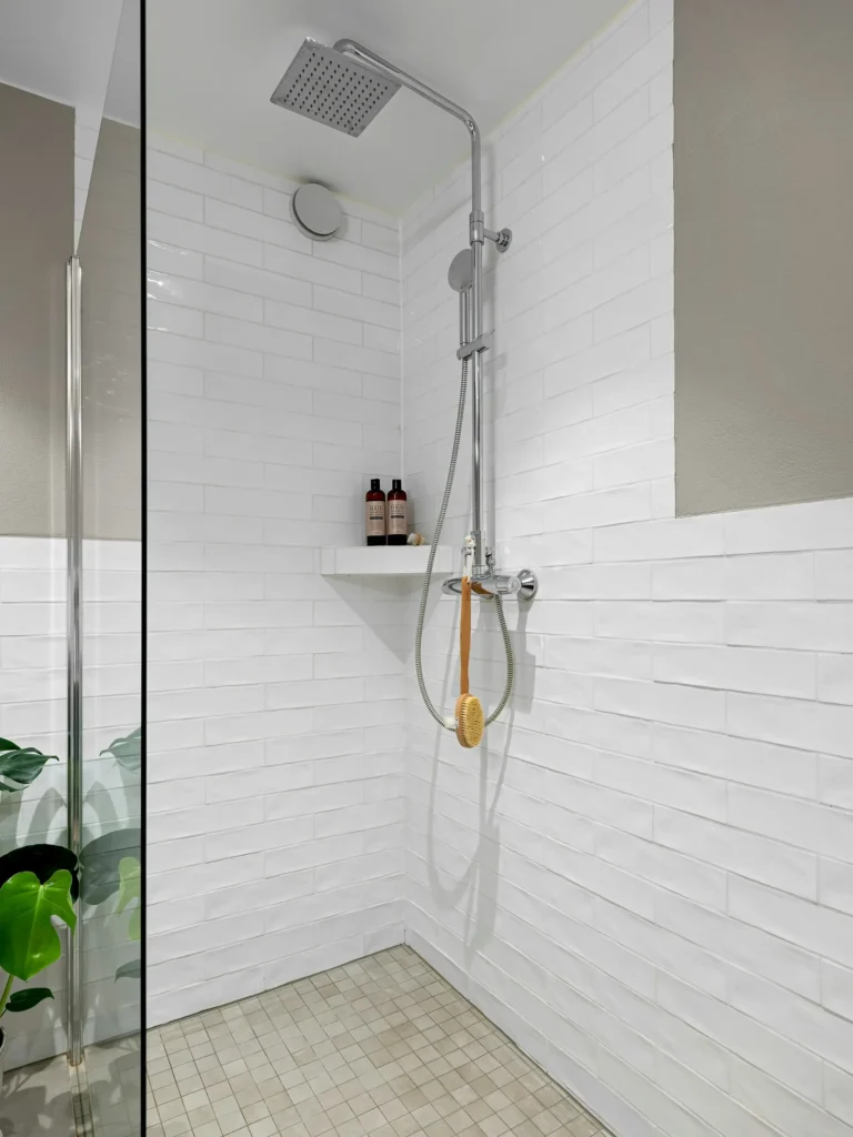 White tiled walk-in shower with a glass door